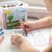 A child coloring a picture with a Choice 230-count bulk school crayon bucket.