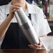 A woman using a Barfly stainless steel cocktail shaker to make a martini.