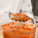 A person using a Vollrath Black Perforated Oval Spoodle to serve meatballs.