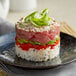 A stack of tuna, avocado, and green onion sushi rolls on a plate made with an Ateco stainless steel round cake/food ring mold.