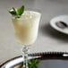 a glass of white liquid with ice and mint leaves