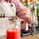 A person using a Barfly stainless steel bar spoon to pour liquid into a glass.