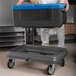 A man using a black and blue Metro Mightylite food pan carrier on a cart.