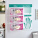 A wall-mounted glove dispenser station holding three boxes of Noble latex gloves with an attached usage guide chart.