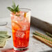 A glass of red DaVinci Gourmet guava syrup with ice and lime slices.