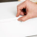 A hand holding a white bakery box.