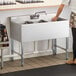 A woman standing next to a Steelton underbar sink.