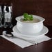 A white bowl of Silver Skillet cream of mushroom soup with a leafy plant on top.