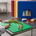A woman slicing a carrot on a colorful cutting board.