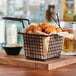 An Acopa black square mini fry basket filled with fried food on a table in a restaurant.