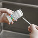 A person in gloves using Serim chlorine test strips to test liquid in a sink.