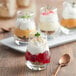 A tray of desserts in Acopa tulip glasses with a spoon.