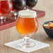 A close-up of a glass of Acopa Belgian beer on a table with chips.