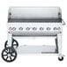 A Crown Verity stainless steel mobile outdoor grill with wheels and a lid.