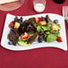 A white plastic Fineline salad plate with strawberries and blueberries.