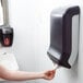 A person putting a paper towel in a San Jamar Ultrafold paper towel dispenser.