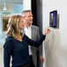 A man and woman using a Durable silver metal wall-mount tablet holder to look at a tablet.