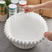 A person holding a Fetco paper coffee filter over a container.