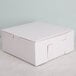 A white cake box with a lid on a white surface.