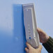 A person using a Durable Sherpa wall-mount reference system to hold a white rectangular object.