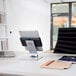 A silver metal tablet holder on a desk with a laptop and tablet on it.