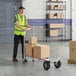 A man pushing a Magliner hand truck with boxes on it.
