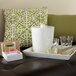 A white rectangular melamine tray with glasses of tea and a water container on a couch.
