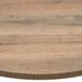 A BFM Seating Relic Knotty Pine round melamine table top with matching edge on a table.