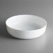 An Arcoroc white opal glass serving bowl on a gray surface.