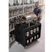 A man standing next to a black Cambro service cart with silver containers.