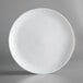 A close up of an Arcoroc white round rimless opal glass plate.