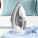 A white Conair Cord-Keeper steam iron on a shirt.