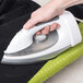 A person using a Conair cord-keeper steam iron on a green cloth.