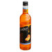 A bottle of DaVinci Gourmet Sugar Free Peach Flavoring syrup on a table with a peach.