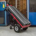 A Magliner motorized hand truck with red and black cylinders on it.