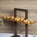 A Cal-Mil crushed bamboo shelf with cookies and flowers on it on a table in a bakery display.