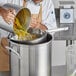 A man using a Choice Fine China Cap Strainer to pour food into a pot.