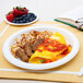 A plate of food with an omelette and sausage on a Bare by Solo paper plate next to a book.