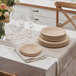 A table set with Bambu bamboo plates and wine glasses on a white tablecloth.