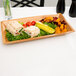 A rectangular bamboo tray with food on a wooden table.