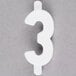 A white number three on a gray surface with "Ketchum Manufacturing 3/4" White Molded Plastic Number 3 Deli Tag Insert"