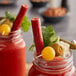 A glass jar of a bloody drink with a garnish and a Benny's Original Meat Straw.