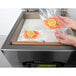 A person using an ARY VacMaster tabletop vacuum packaging machine to seal a bag of fish with lemon slices.