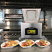 An ARY VacMaster VP320 tabletop vacuum packaging machine with the lid open on a counter with three plates of food.