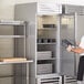 A man opening the left-hinged door of a Beverage-Air reach-in freezer.