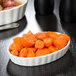 A CAC white fluted oval serving bowl filled with food on a table.