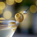 A martini with Belosa Cornichon Pickle Stuffed Olives on a stick.