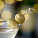 A close-up of a martini glass with Belosa Garlic Stuffed Queen Olives in it.