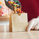 A person scooping nuts and raisins into a brown American Metalcraft mini snack bag.