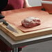 A person cutting a piece of meat on a cutting board.